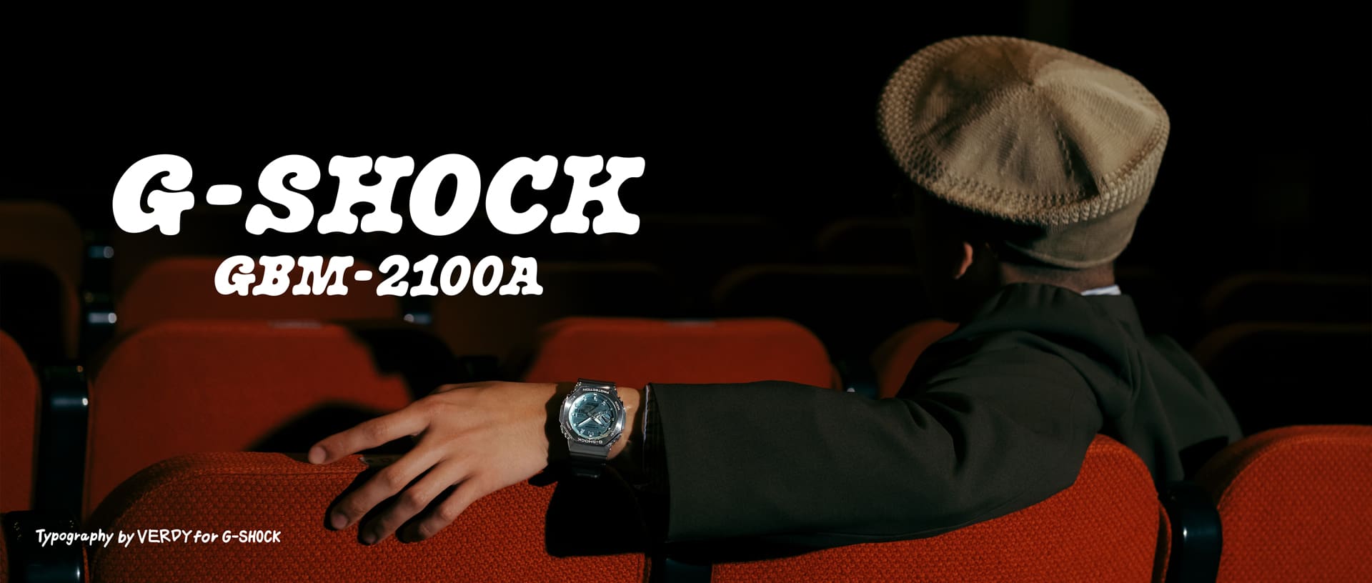 Şık bir iç mekanda deri koltukta dinlenen ve G‑SHOCK GBM‑2100A takan kişi.