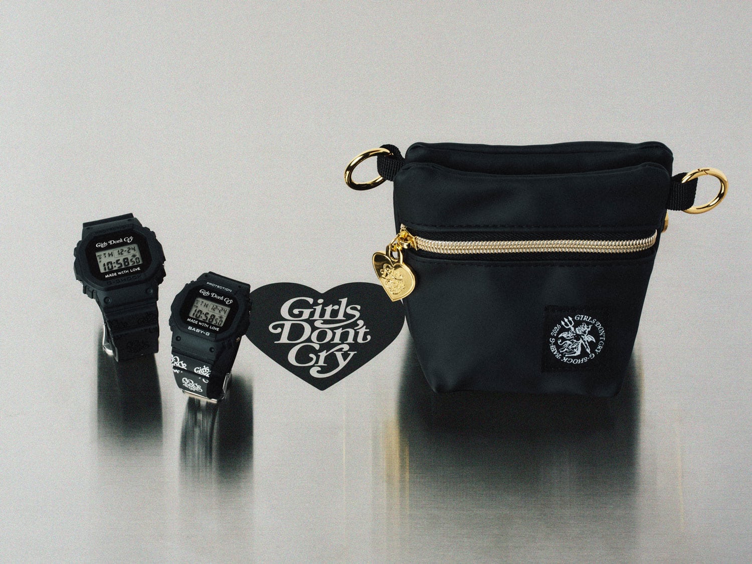 A product photo of two black G-SHOCK watches and a Girls Don't Cry pouch displayed together.