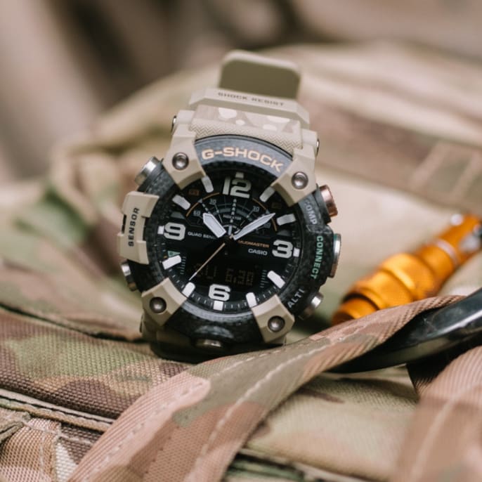 The collaboration model by G-SHOCK and the British Army on a uniform next to a carabiner.