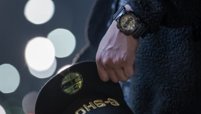A person carries a cap in their hand as well as the collaboration model GM-110NE-1AER