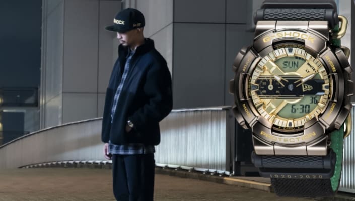 The collaboration model by G-SHOCK and NEW ERA in the foreground; behind it, a man with a cap and watch in front of a skyscraper is visible.