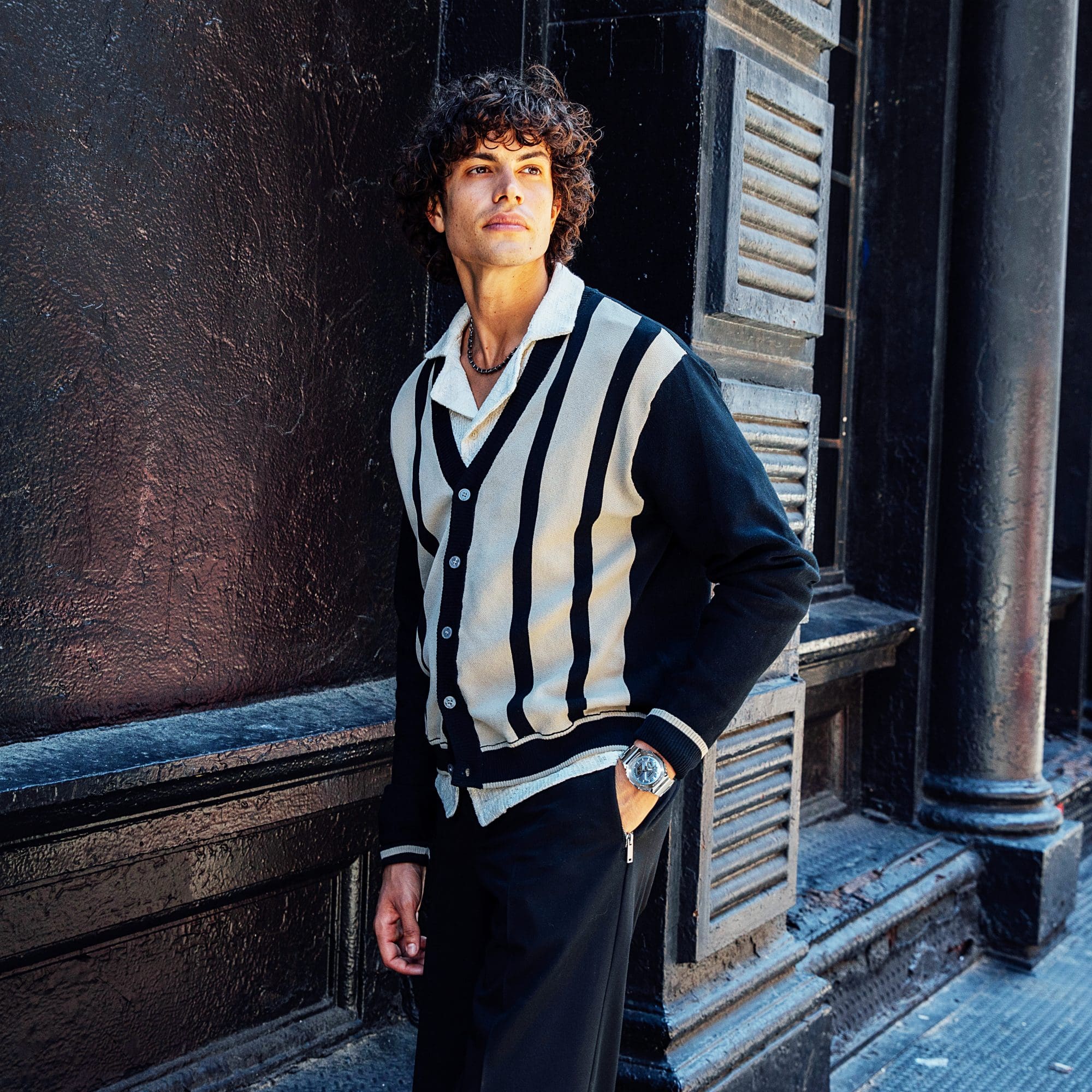 Medium shot of a man in a striped shirt standing in the street wearing a G-SHOCK GM2110D-2A watch denoting style