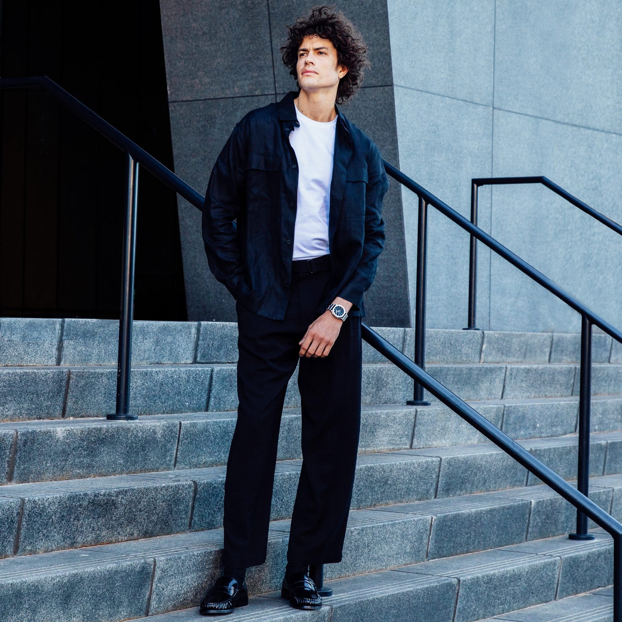 A man standing on stairs wearing casual attire sporting a G-SHOCK GM2110D-2B watch