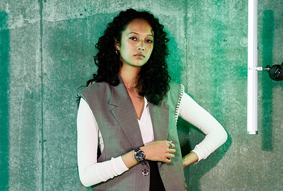 Woman in green light wearing G-SHOCK GMS110 metal covered analog digital watch