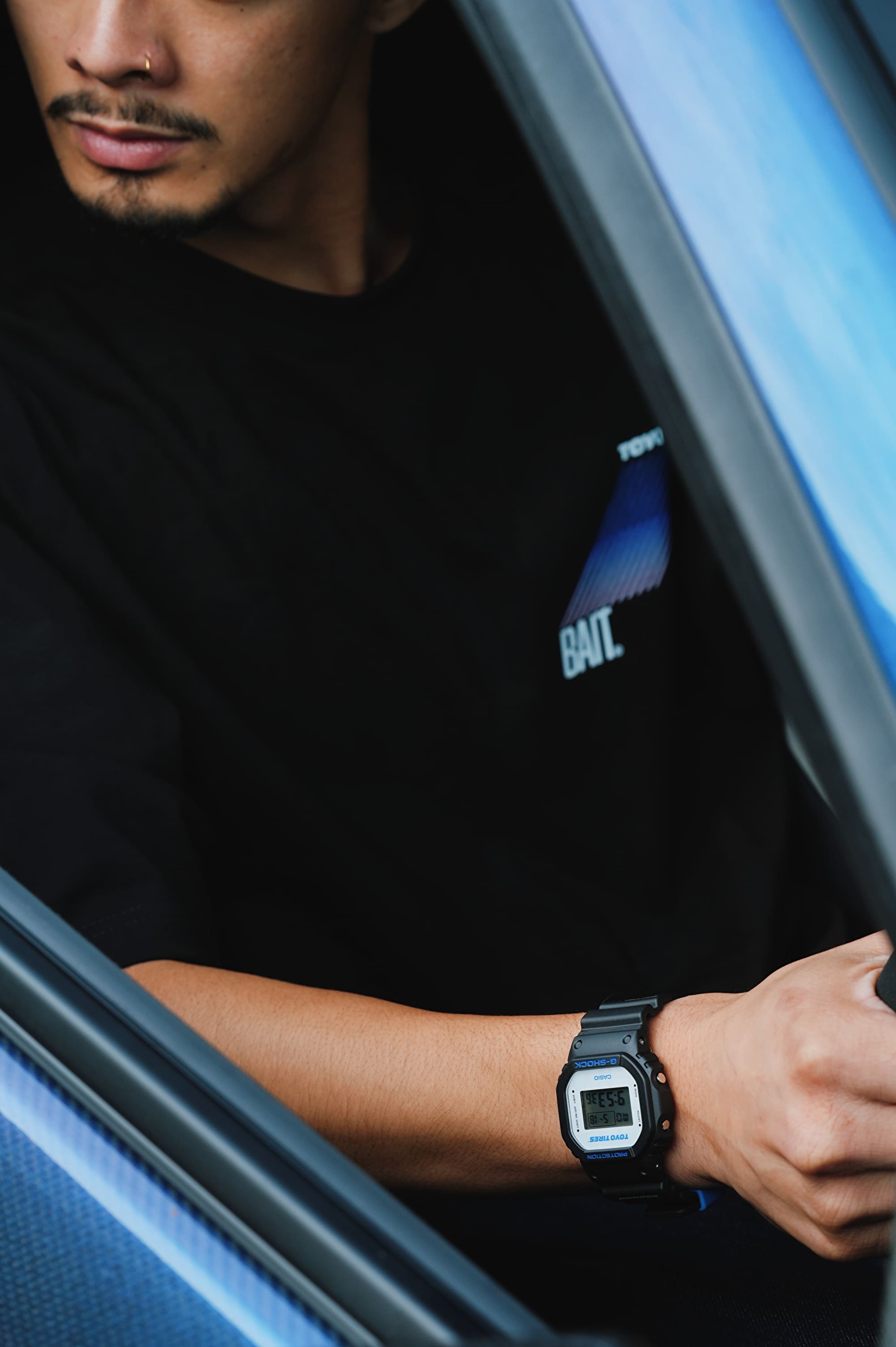 Man seated in a care waring a G-SHOCK x TOYO TIRES DW5600TT25-1 