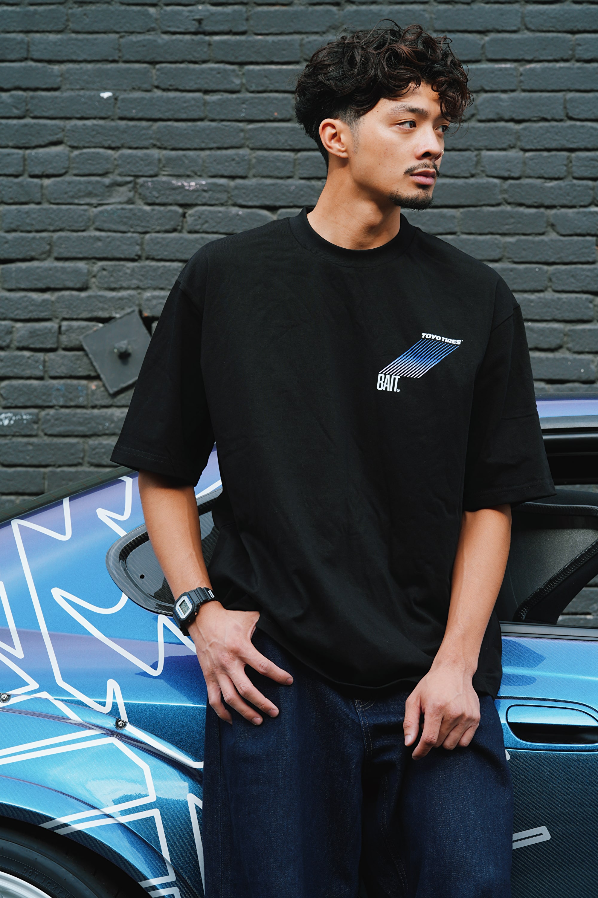 Man leaning on a care wearing G-SHOCK x TOYO TIRES DW5600TT25-1 