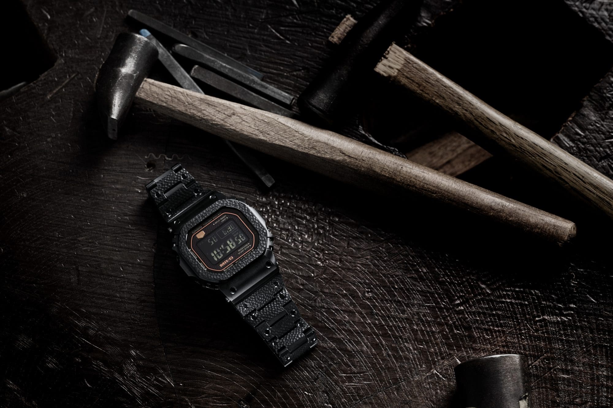 Photo showing a hammer and chisel used for hand-hammering technique alongside the MRG-B5000 "Tsuiki" Limited Edition watch