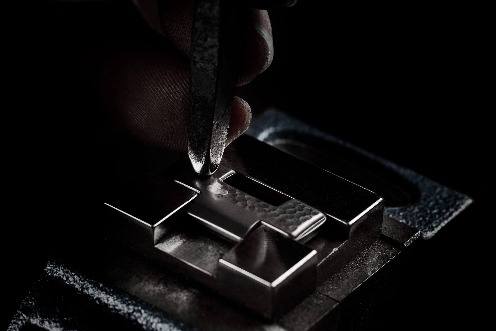 Photo showing a chisel engraving a hand-hammered pattern