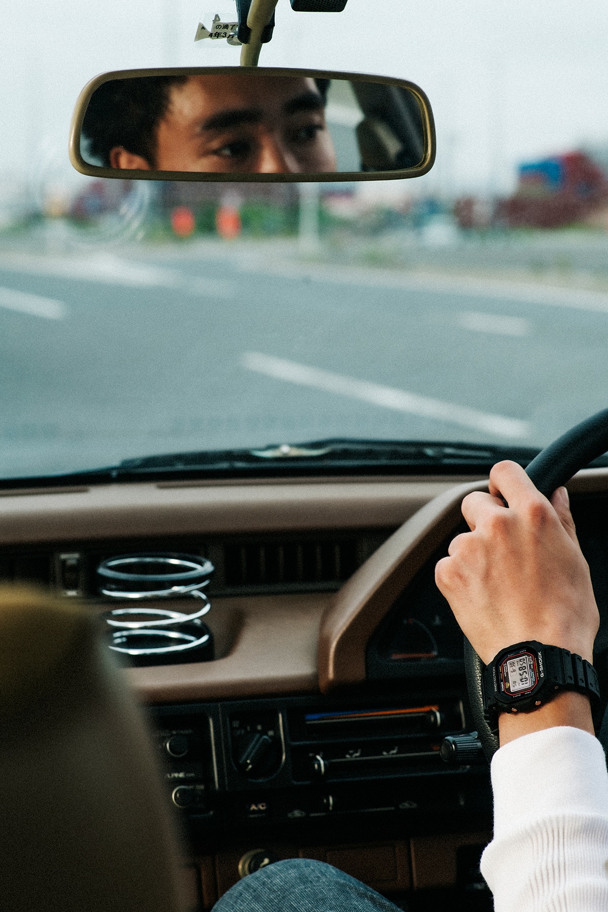 A man wearing a G-SHOCK watch driving a car.