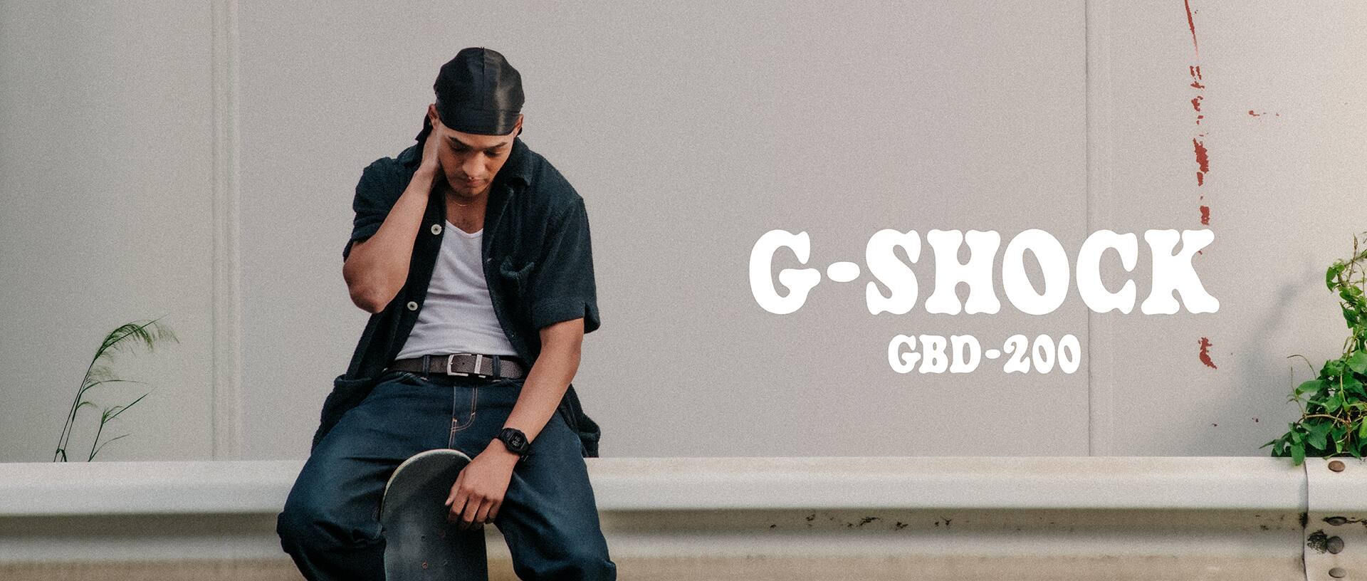 A man holding a skateboard sitting on a guardrail.