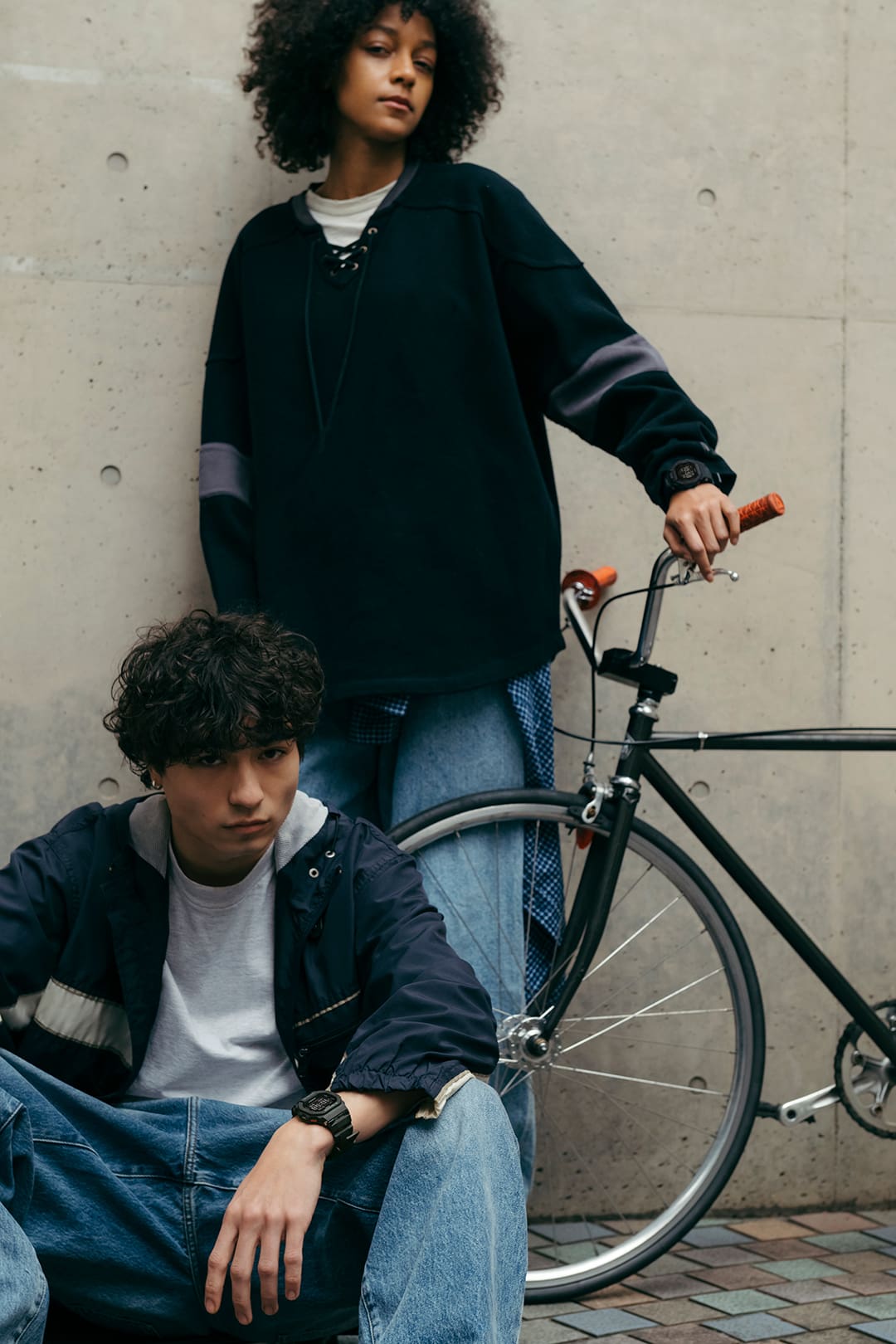 Person leaning casually with bicycle wearing G-SHOCK GBD-200 in street setting.