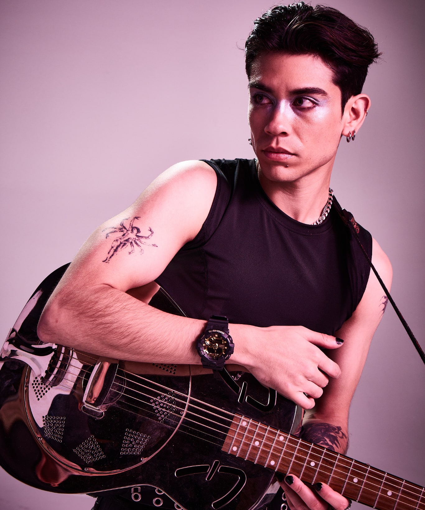Musician in a sleeveless black top holding a guitar and wearing a black G-SHOCK watch.