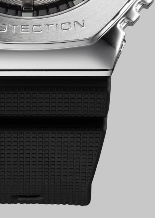 Nahaufnahme des Übergangs von silberfarbenem Edelstahlgehäuse und schwarzem Strukturarmband der Casio G-Shock GM-2100-1A Armbanduhr