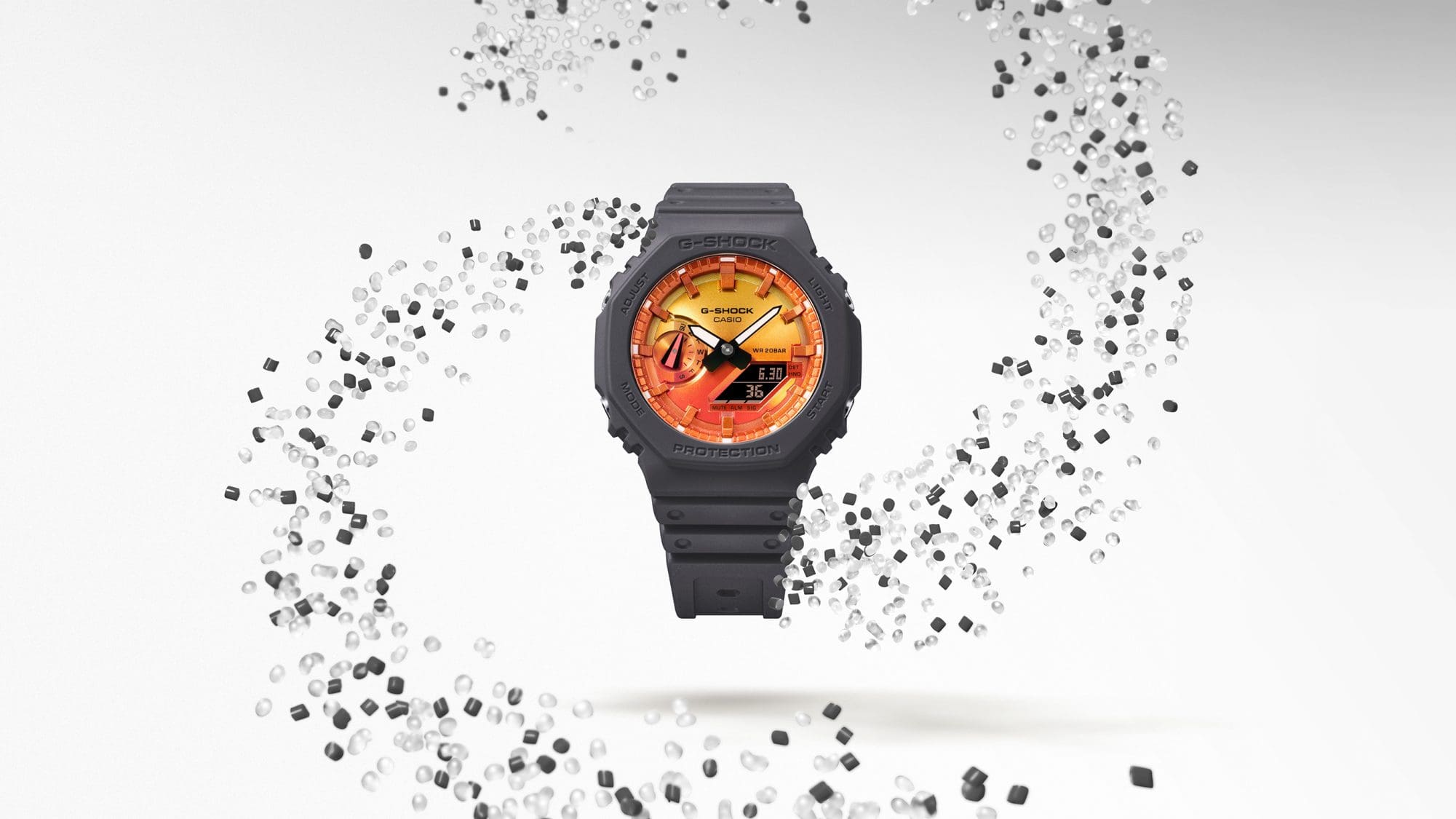 GA-2100FL-8A SorgfältiDie GA-2100FL-8A Hybriduhr umgeben von einem Wirbel aus durchsichtigen und grauen Resin-Granulatge Materialauswahl: Biobasiertes Harz