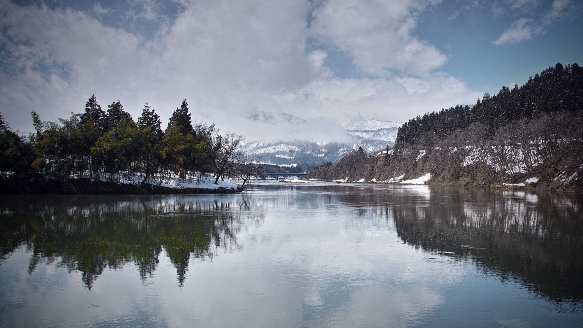 Ein klarer See umringt von Gebirgen und einem Wald