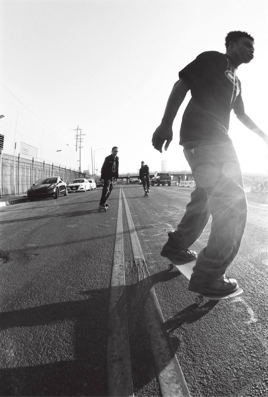 Schwarz-Weiß-Foto von drei Männern, die auf einer Straße Skateboard fahren