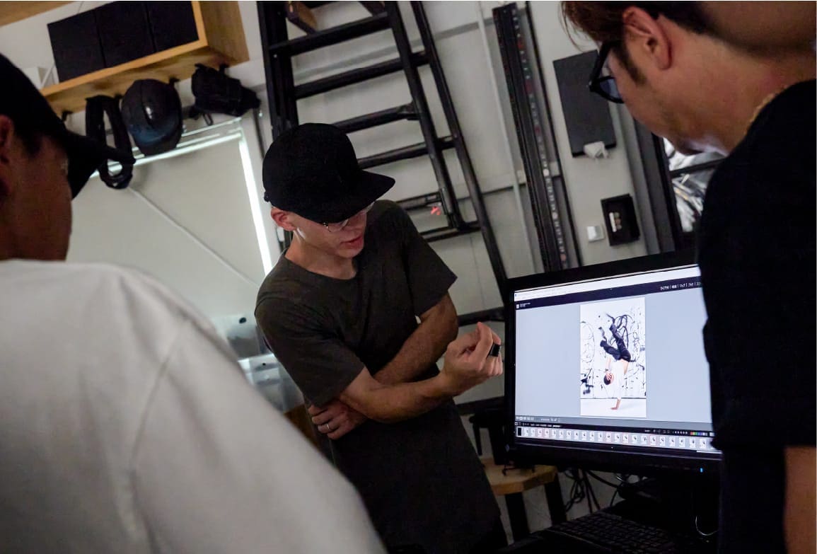 Drei Männer stehen in einem Atelier vor einem Computer-Bildschirm