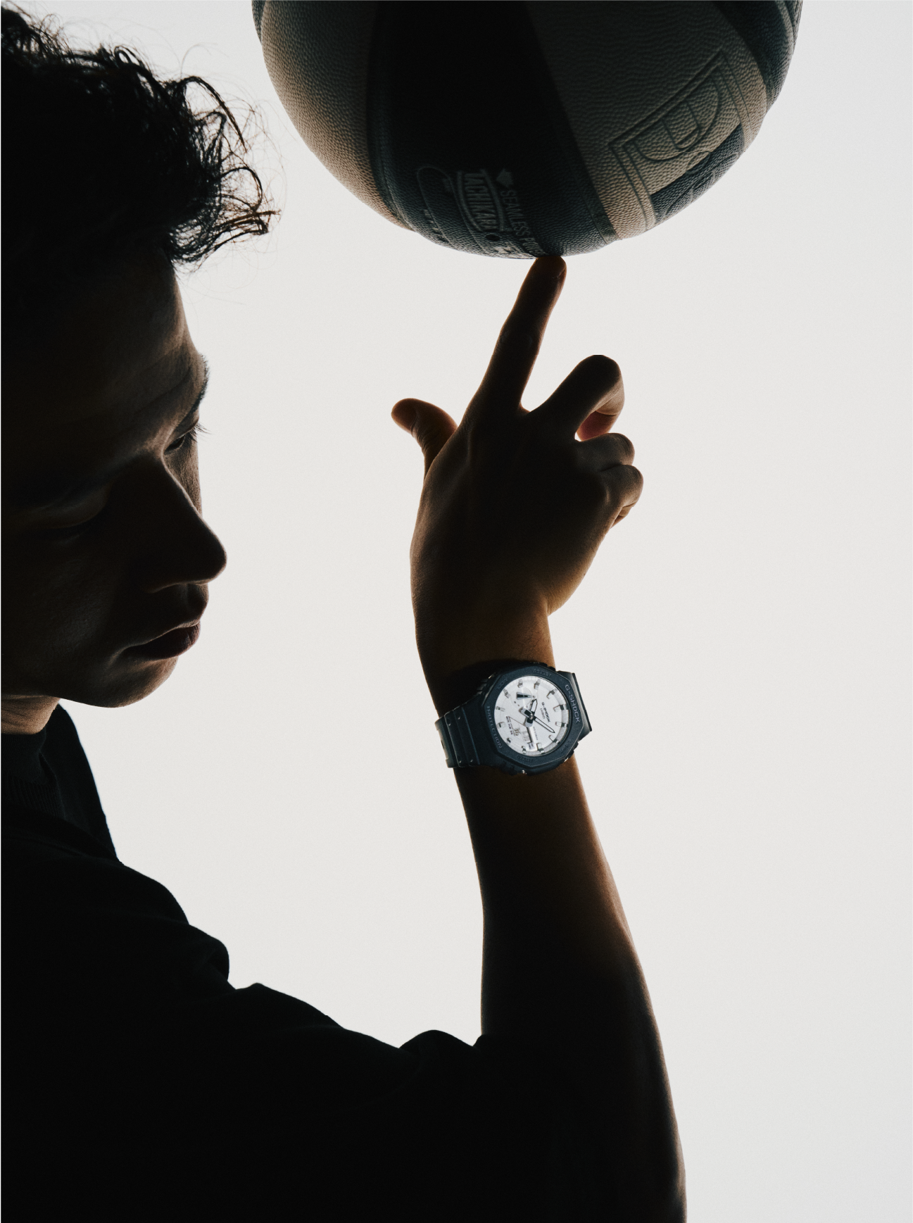 Freestyle-Basketballspieler Kengo Maeda balanciert einen Basketball auf seinem Zeigefinger, er trägt eine schlanke und sportliche GA-2100WD Armbanduhr.