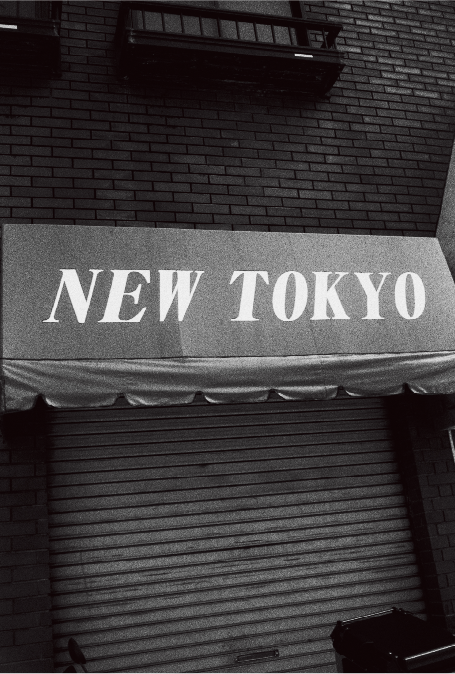 Schwarz-Weiß-Foto von Yusuke Yamatani mit dem Schriftzug New Tokyo auf einer Markise.