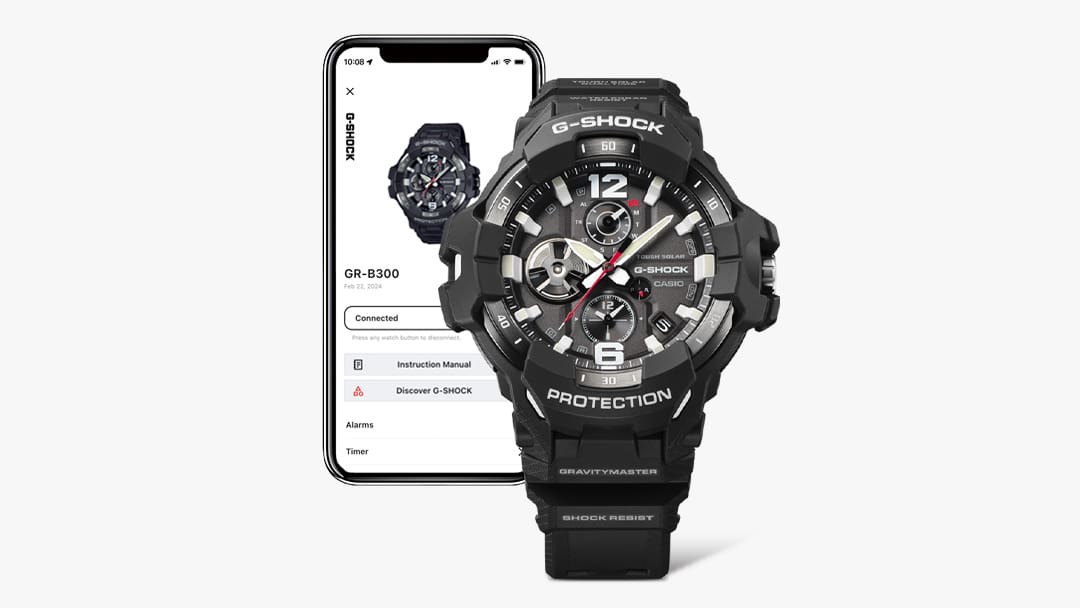 Eine schwarze Master of G GR-B300 Bluetooth®-Uhr vor einem Smartphone, auf dessen Display Informationen zur Uhr zu sehen sind