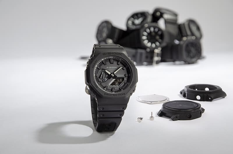 Eine schwarze Casio G-Shock Damenuhr vor Einzelteilen aus denen sie sich zusammensetzt