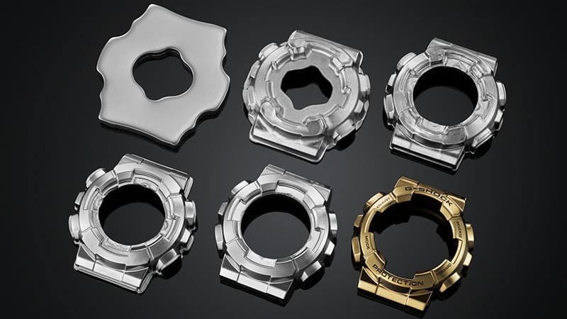 The metal bezel in six different stages of processing, from the rudimentary, silver-coloured blank to the gold-coloured, finished bezel