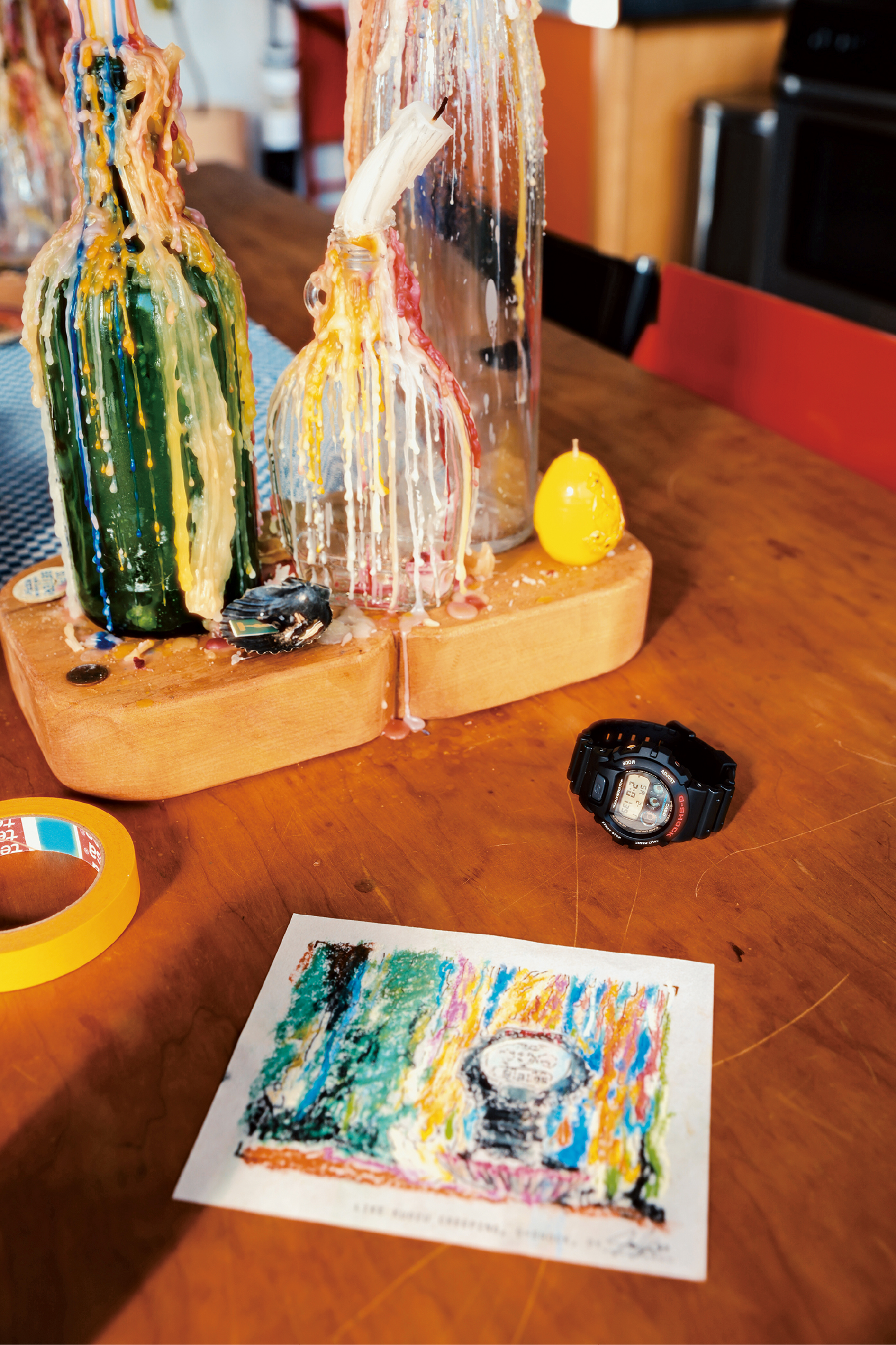 Julian's desk with burned candles next to a G-SHOCK DW-6900 wristwatch with round massive case and a digital display