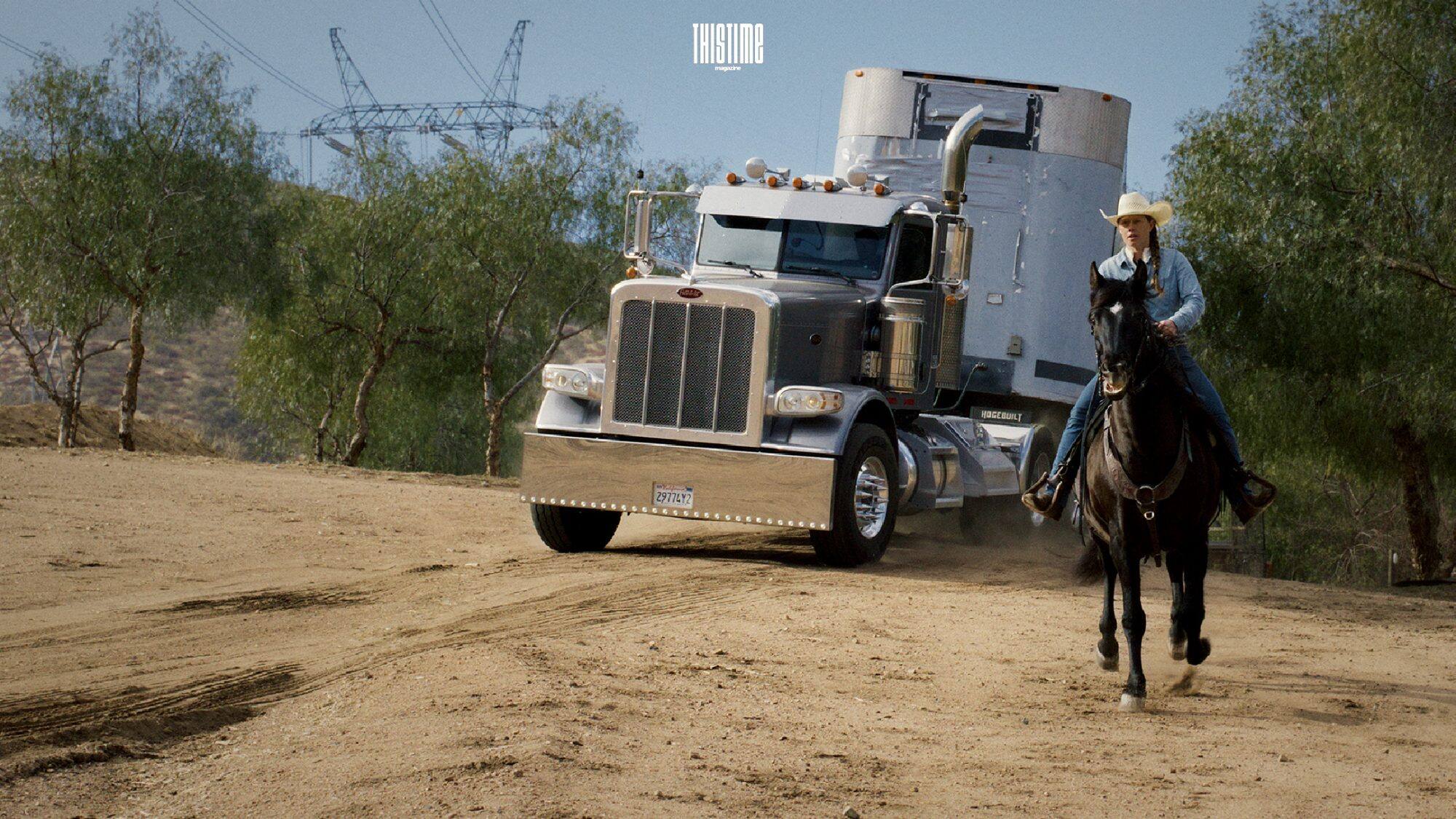 A Semi-trailer truck next to a man riding on a horse
