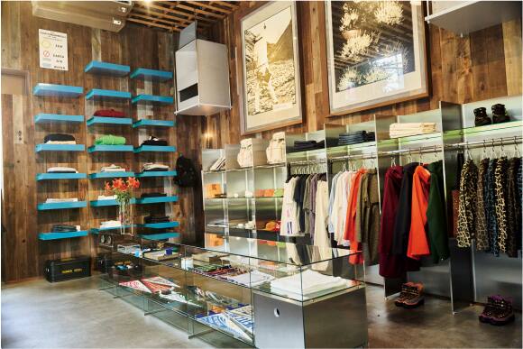 Interior view of the Nakameguro store with wooden walls, shelves, glass display cases, and clothing hanging on racks.