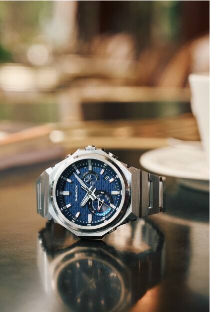 Close-up of the G-Shock GST-B1000D-2A with a blue, analogue bezel on café table.
