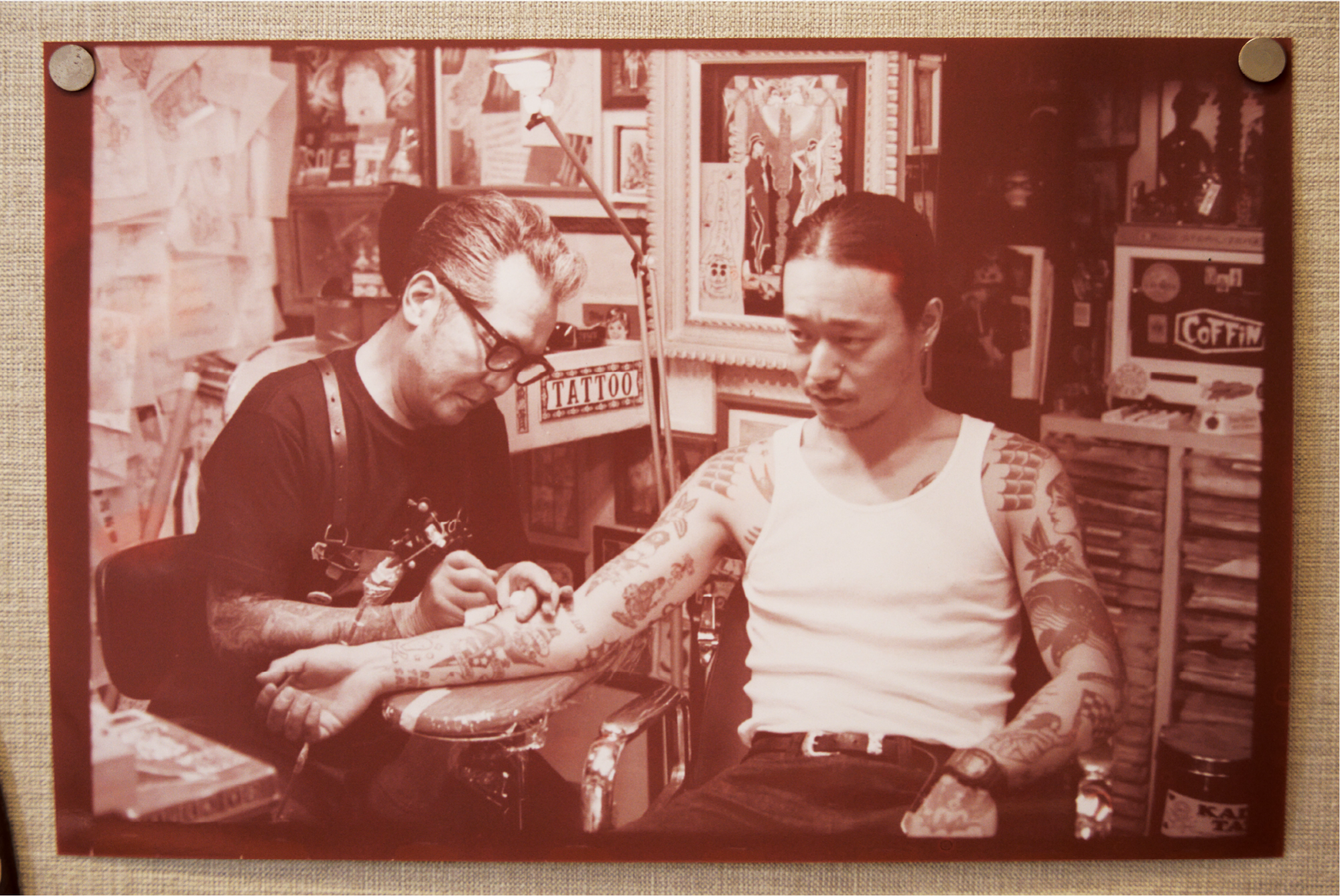A snapshot in sepia colours of Len Yamada getting tattooed himself.