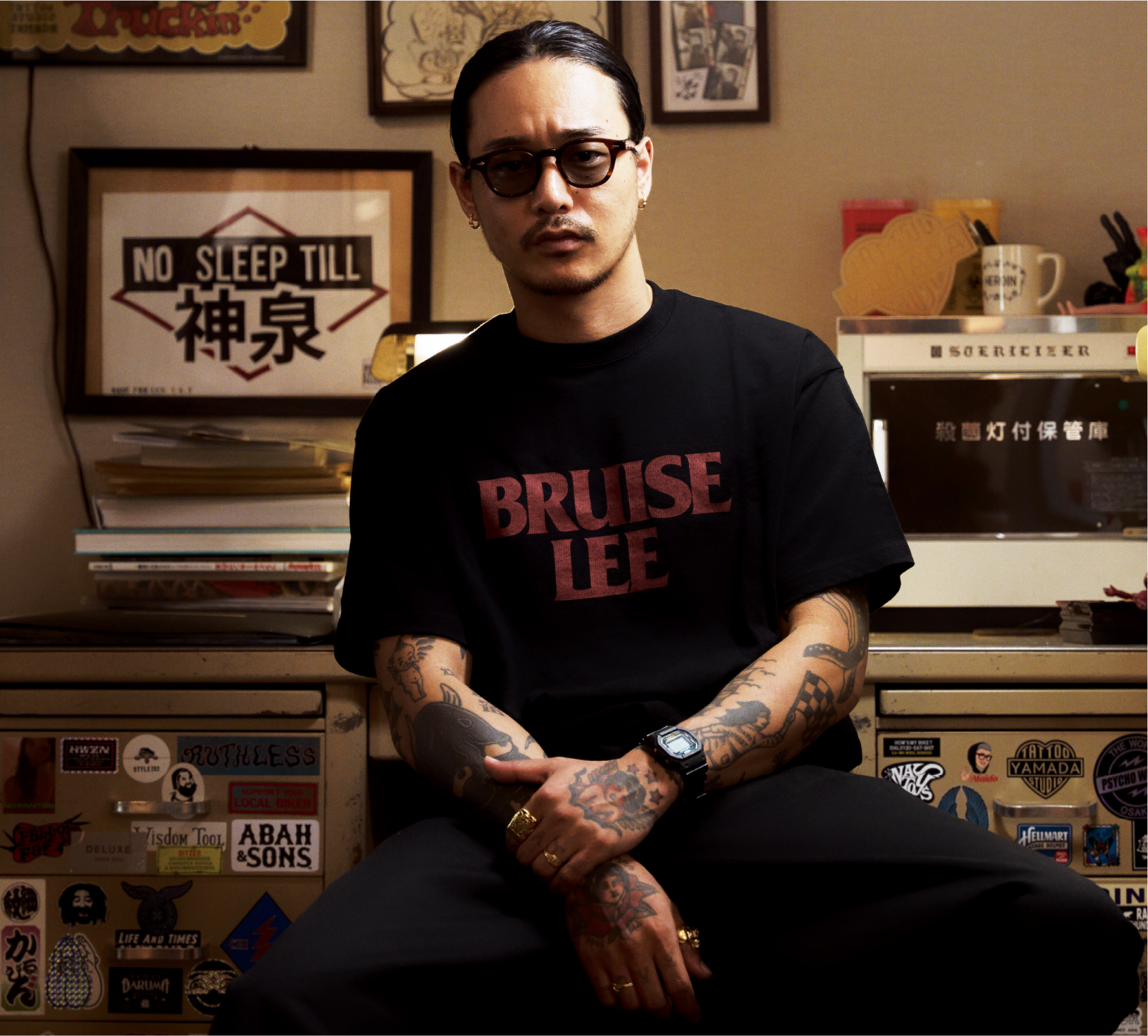 Len Yamada sits on a chair and wears the digital CASIO DW-5600C-1 watch in black.