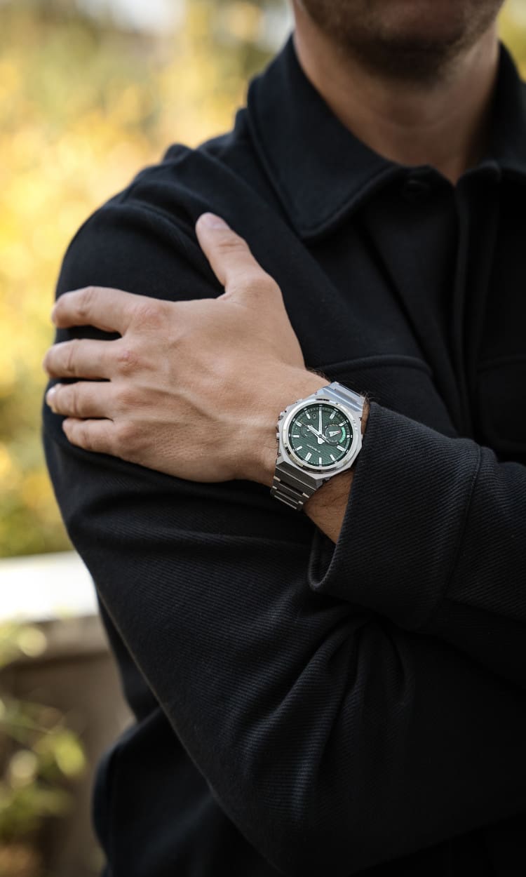 Medium shot of a man in a black shirt wearing the GST-B1000 wristwatch with a dark green analog dial.