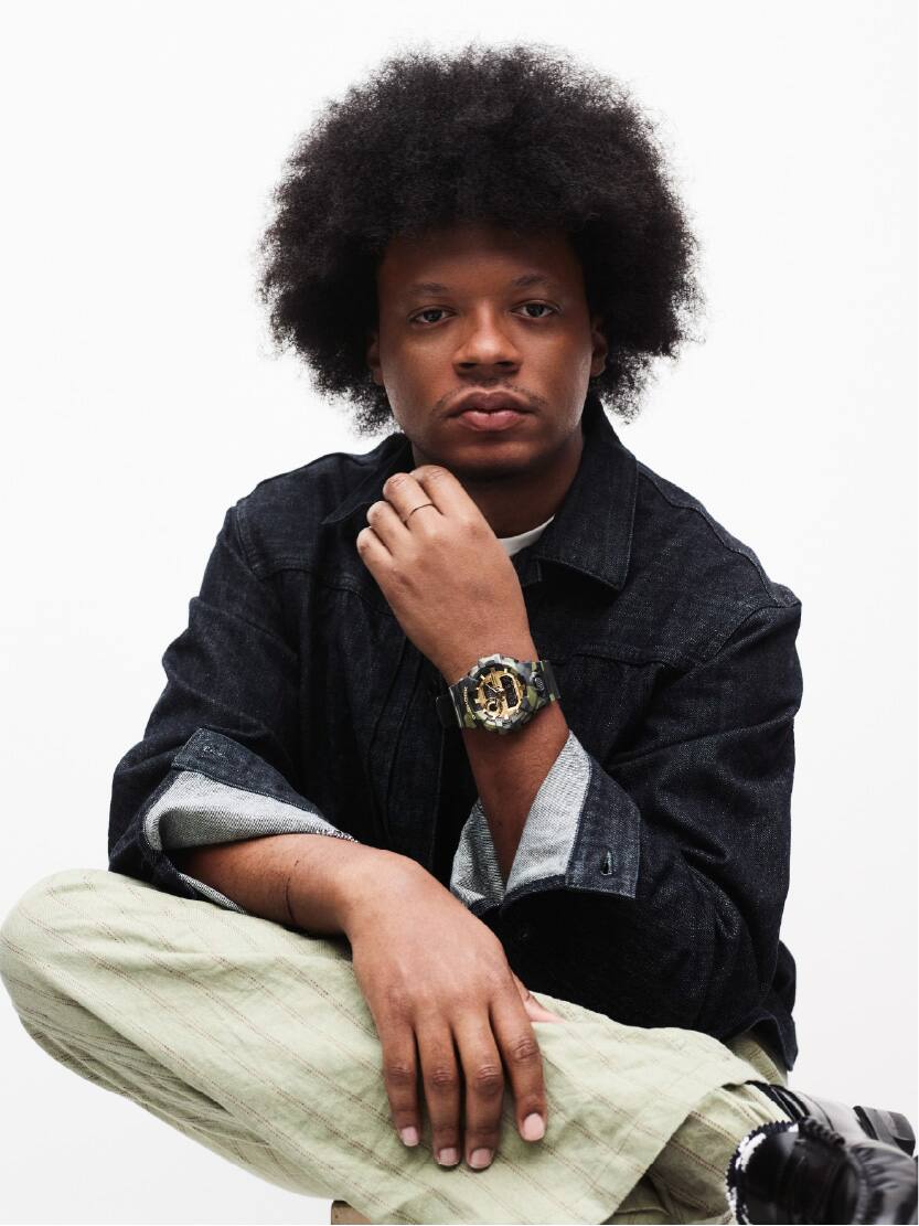 A male is wearing G-SHOCK GA-700CMG-3A on his wrist.