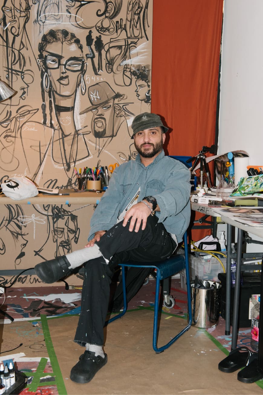 Artist Stephen Palladino seated inside his studio surrounded by artwork.