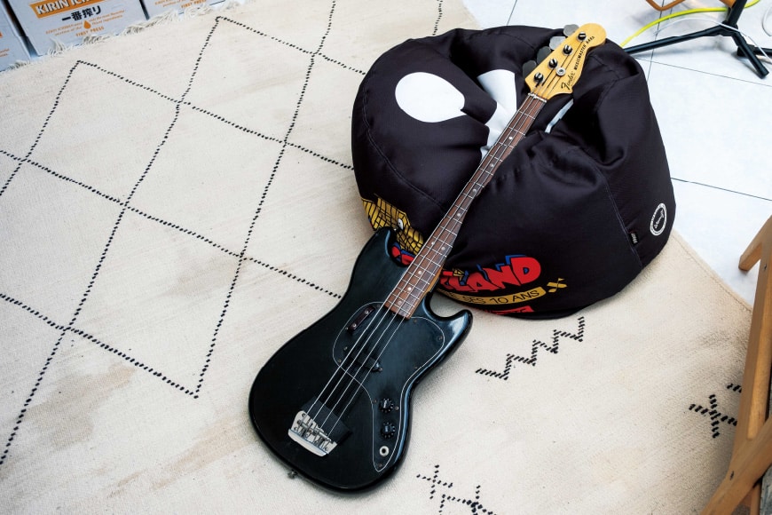 Close-up of a black guitar placed on the floor.