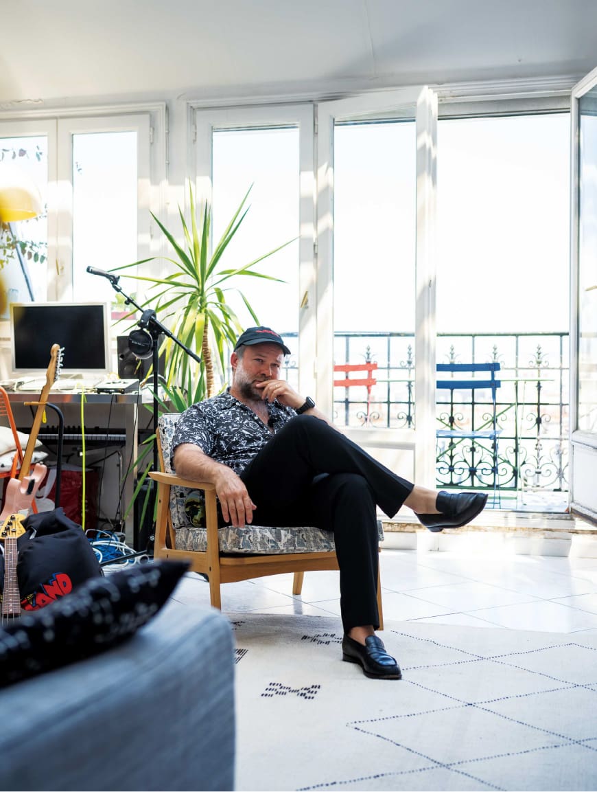 Artistic Director sitting indoors in a bright living space.