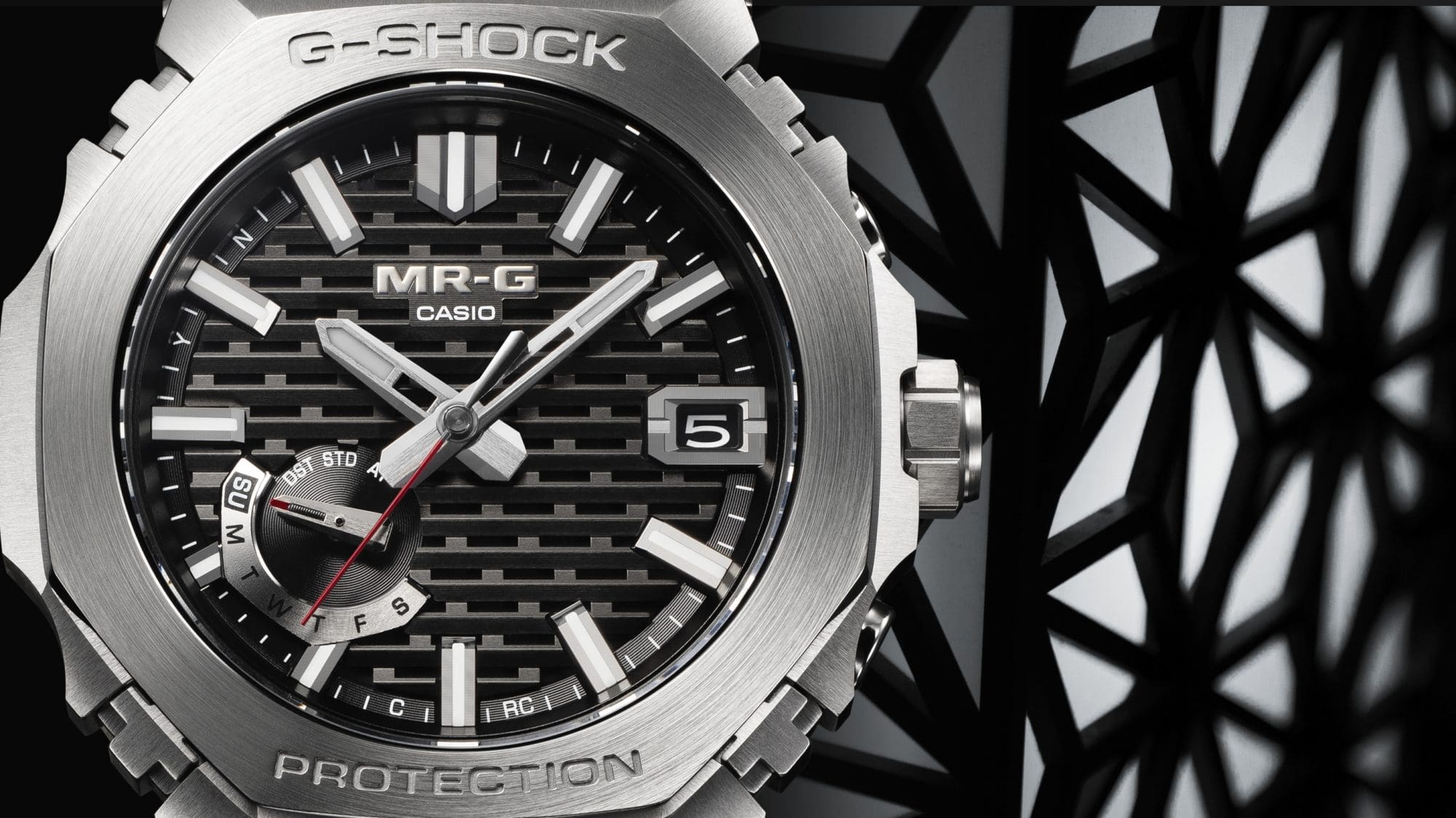 G-SHOCK MRGB2100D-1A titanium watch close up of watch face next to black latticework denoting traditional Japanese kigumi style
