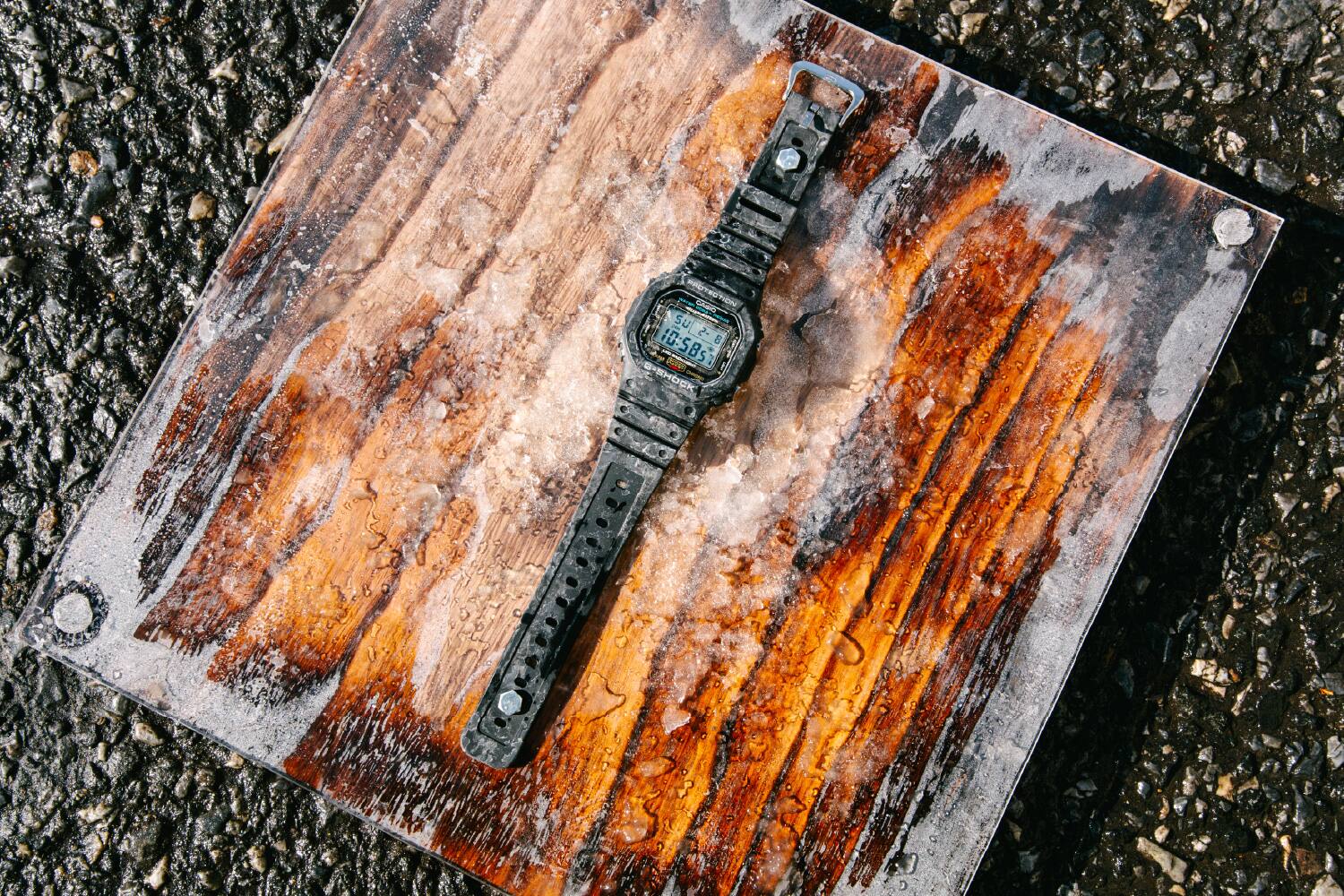 Un reloj G-SHOCK descansa sobre una placa de metal desgastada cubierta de hielo.