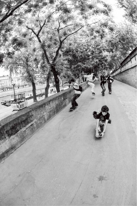 Un joven skater recorre un spot de skate arbolado de París a lo largo de un paseo junto al río.