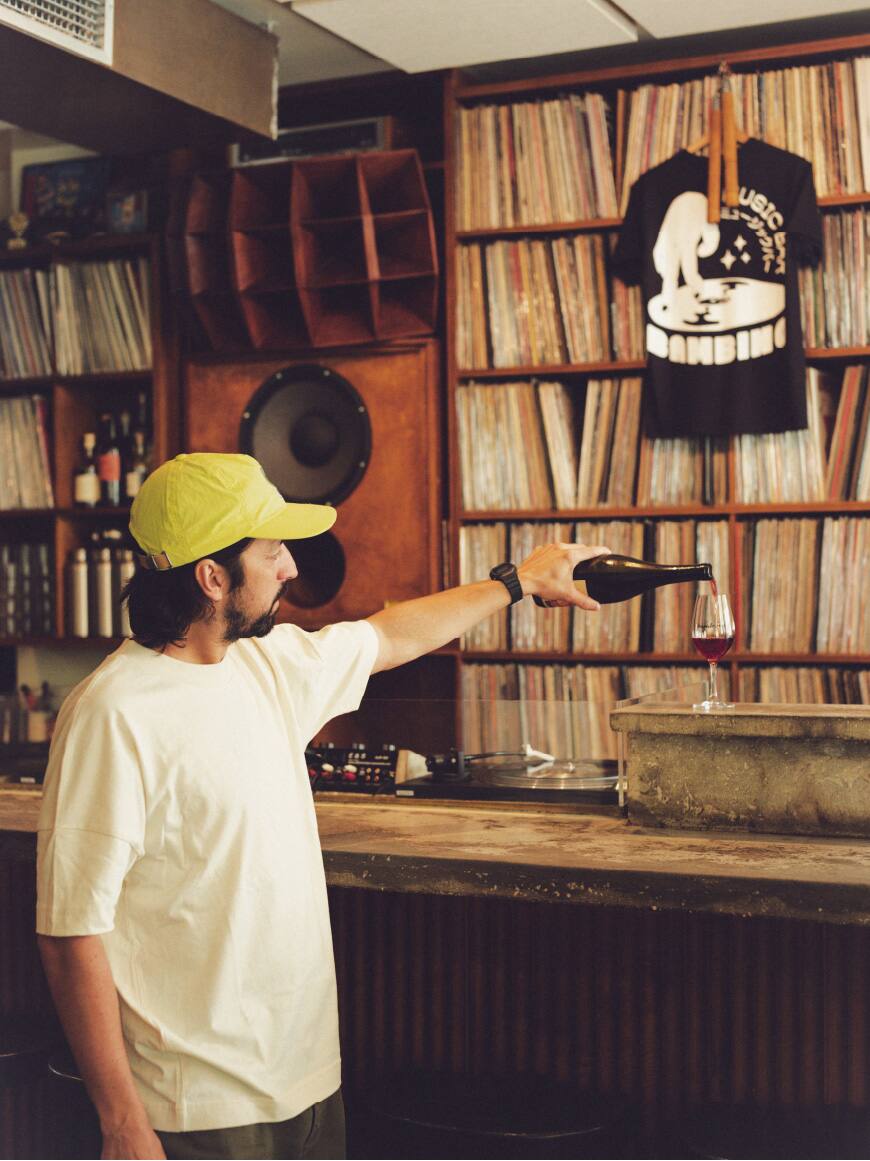 Esta es una foto de un empleado seleccionando discos en Bambino, una cafetería parisina conocida por su cuidada selección musical y su cultura del café.