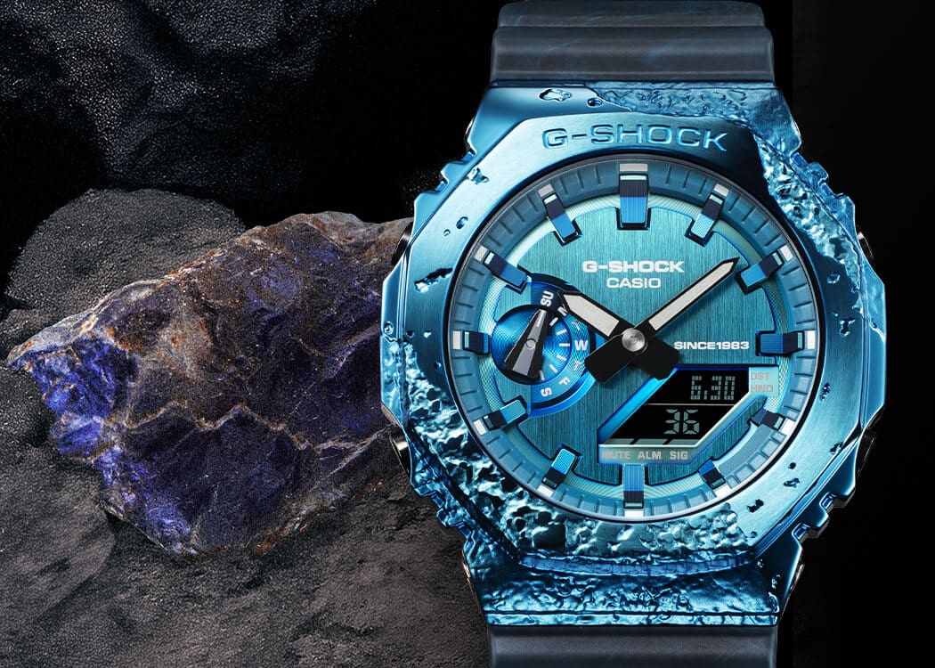 GM-2140GEM-2A El reloj aniversario GM-2140GEM-2A, con su brillante color azul, junto a una piedra de cordierita azul brillante.