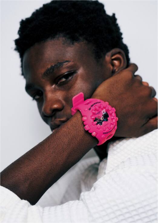 Primer plano de un hombre que se sujeta el cuello y lleva en la muñeca el G-Shock GA-V01 de color rosa intenso.