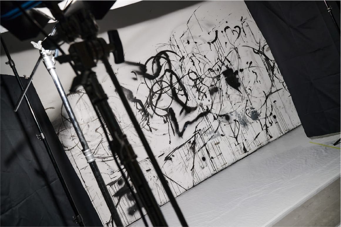 Una pared blanca de un estudio pintada con graffiti negro.