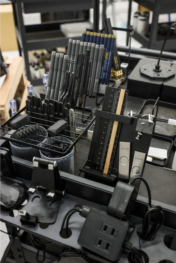 Escritorio en un estudio con bolígrafos, tazas y cables de carga.