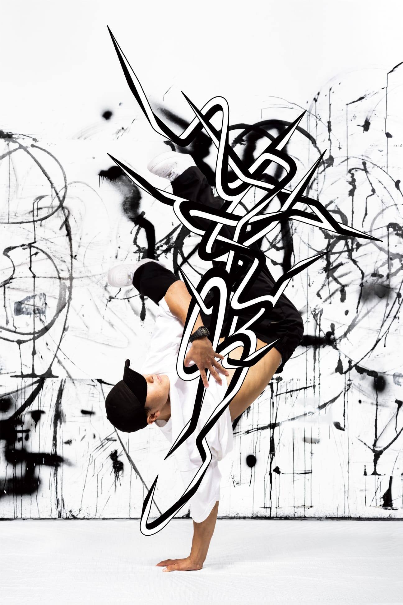 Bailarín de break dance vestido de blanco y negro en una posición de parada de manos frente a un mural de arte callejero en blanco y negro.