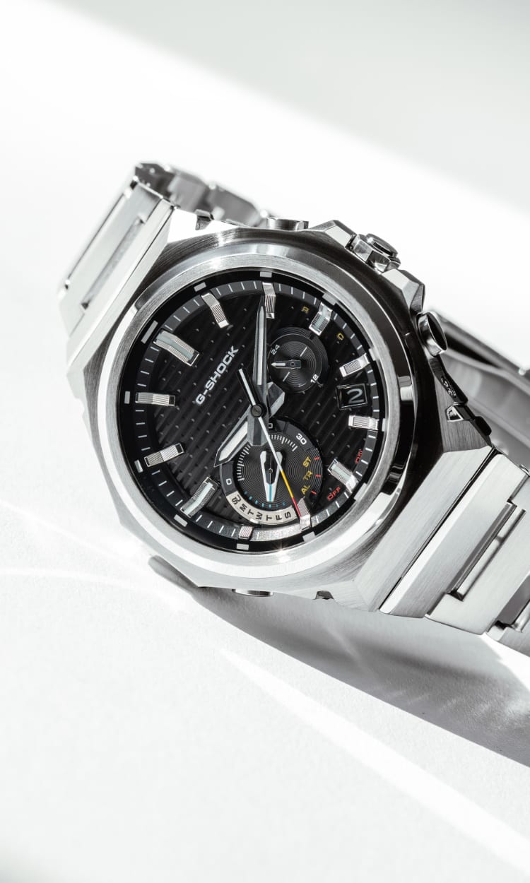 Primer plano del reloj plateado GST-B1000 con esfera negra de G-SHOCK sobre una mesa blanca