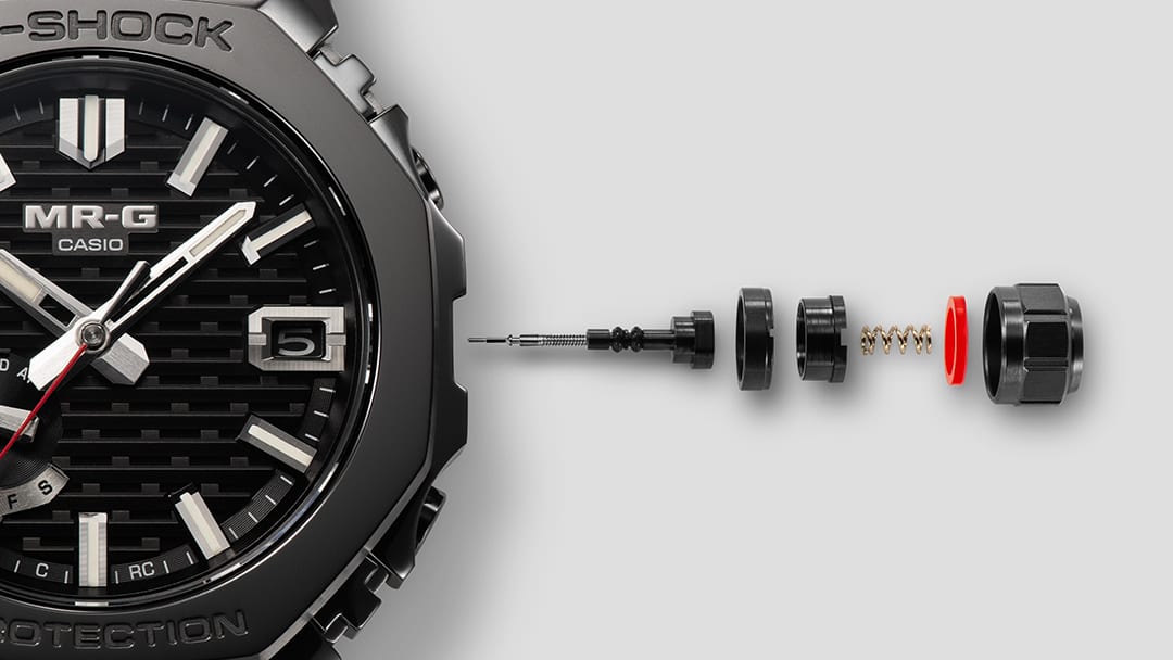 Detalle del bisel del MRG-B2100B, con la corona desmontada en sus partes individuales a su lado.