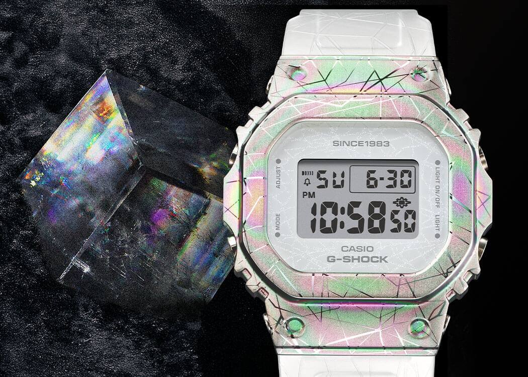 GM-S5640GEM-7 La montre anniversaire GM-S5640GEM-7, d'un blanc chatoyant, à côté d'un cristal de calcite étincelant