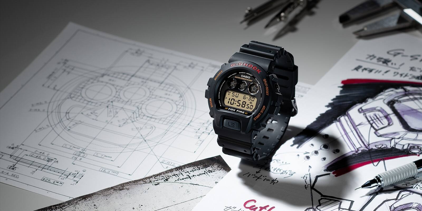 La montre-bracelet Casio G-Shock DW-6900B-9 sur une table couverte de dessins conceptuels ainsi que d'un stylo, d'un compas et d'un outil de mesure